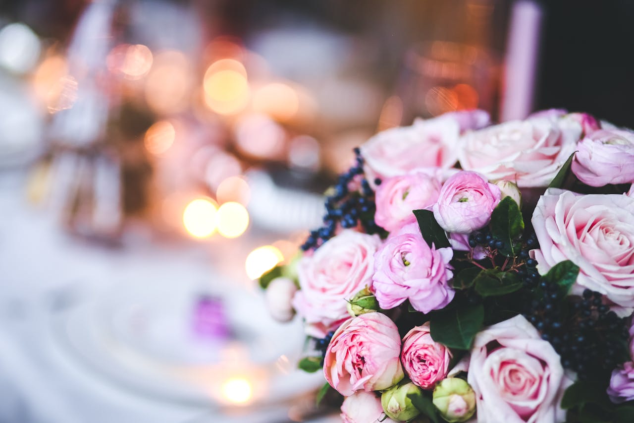 Close-up of a pink rose and ranunculus bouquet with soft bokeh lights.