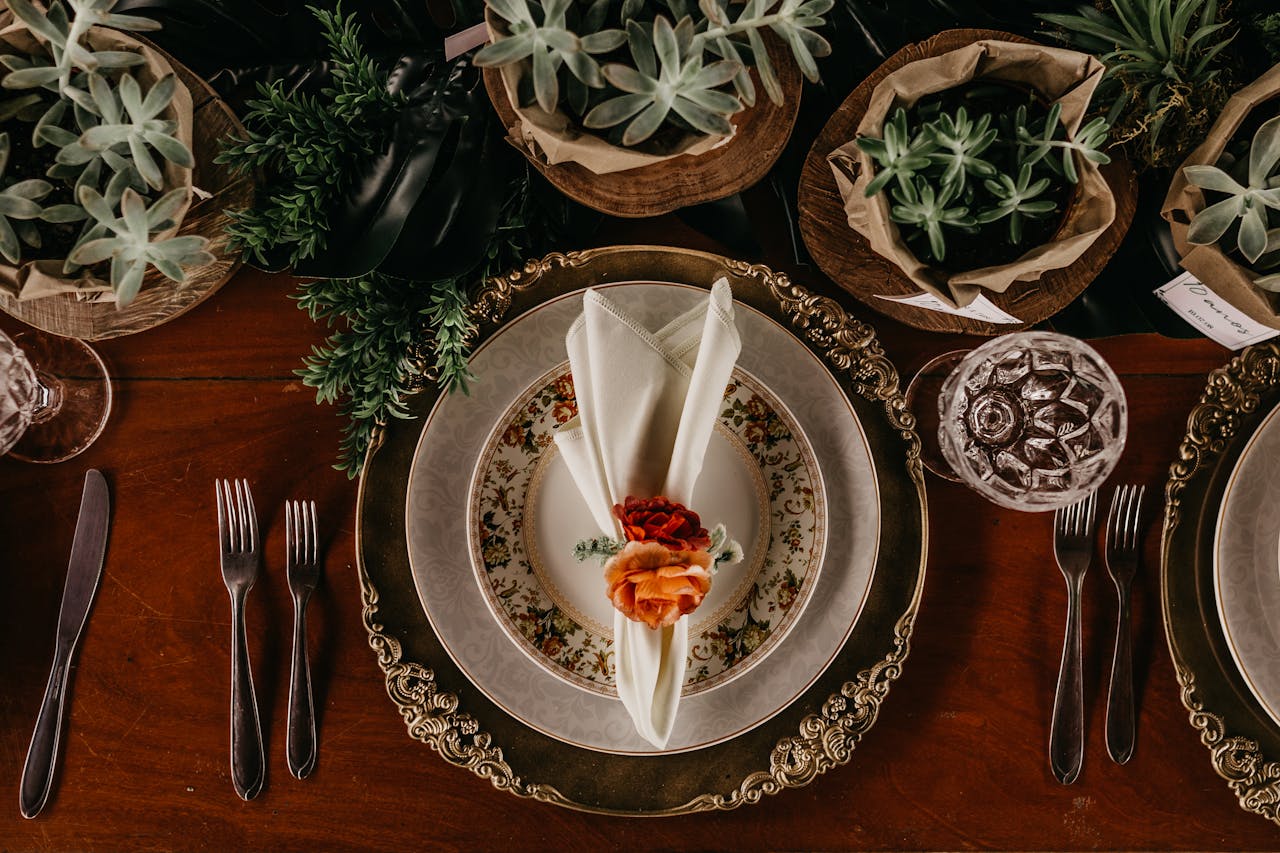 A beautifully arranged dining table with ornate plates, cutlery, and succulents for a sophisticated vibe.