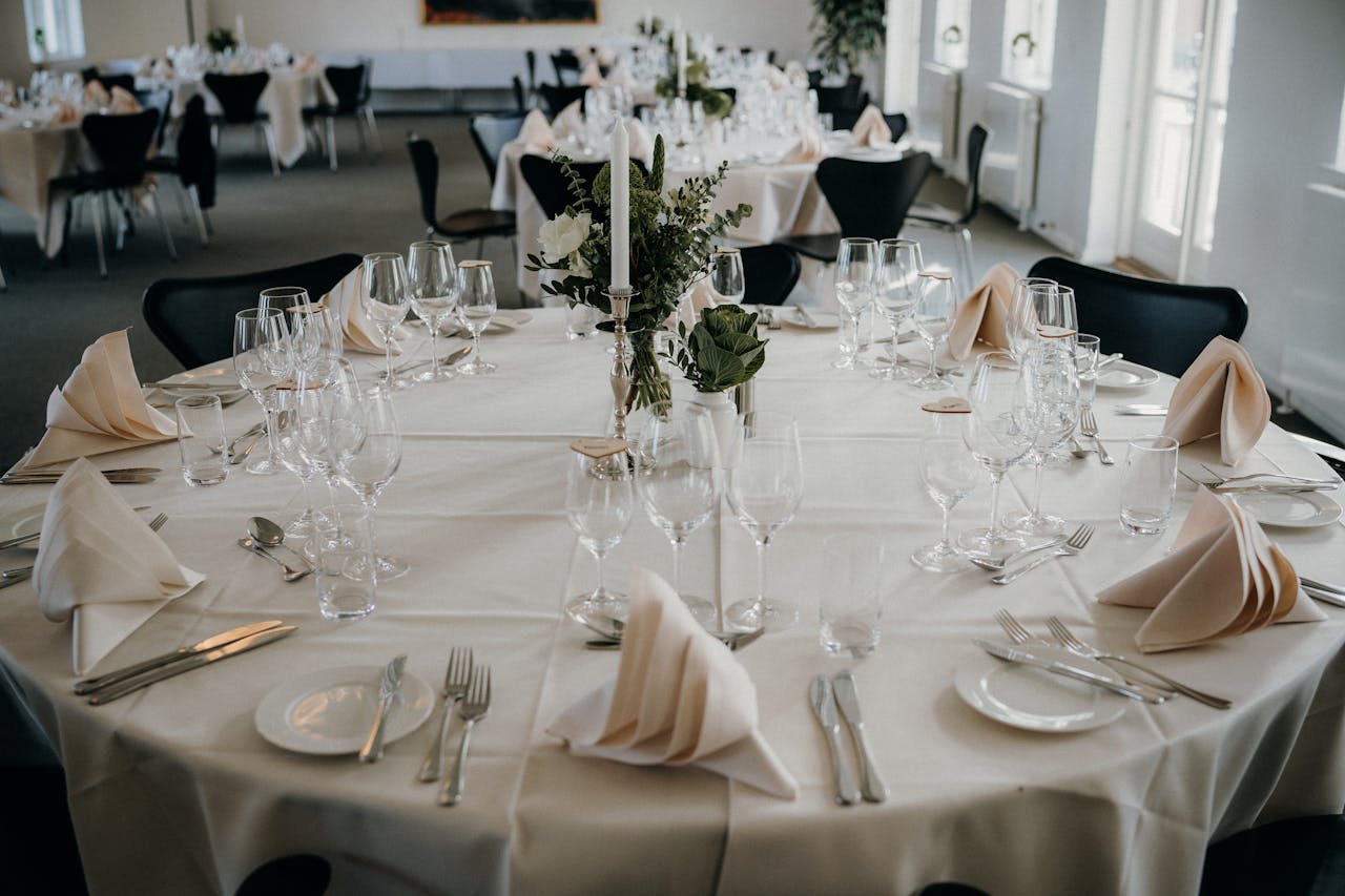 A beautifully arranged dining table setup for a wedding reception with elegant tableware and floral centerpiece.